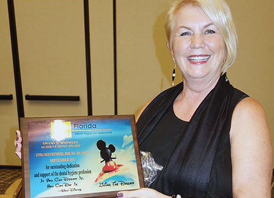 Linda Meeuwenberg holding the 2017 Swann D. Knoles Achievement Award at the Florida Dental Hygiene Association Annual Symposium, where she also served as a speaker. Presented for “outstanding dedication and support of the dental hygiene profession.