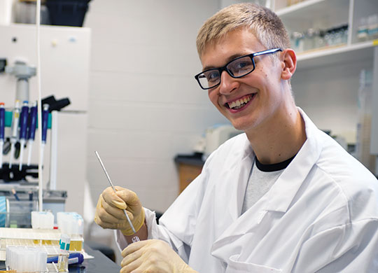 2017 Student Research Fellowship student participant Austin Vanwyk posing in a biology lab.