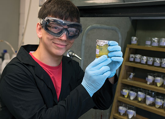 2017 Student Research Fellowship student participant Brandon Mihelich in chemistry lab holding a specimen in a jar.