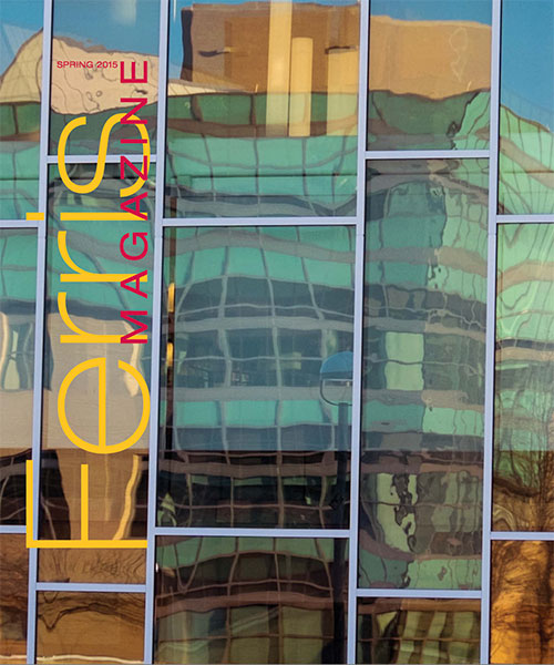 Cover of the Spring 2015 Ferris Magazine, featuring a reflected image of Ferris' FLITE building seen in the glass of adjacent University Center Window.