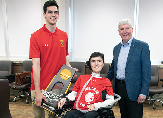 (Left to right) Michael Peterson and Mitchell Peterson, both of the Ferris State men’s basketball team, show the team’s championship trophy to Gov. Rick Snyder after Snyder’s Marshall Plan presentation at Ferris State on April 6.